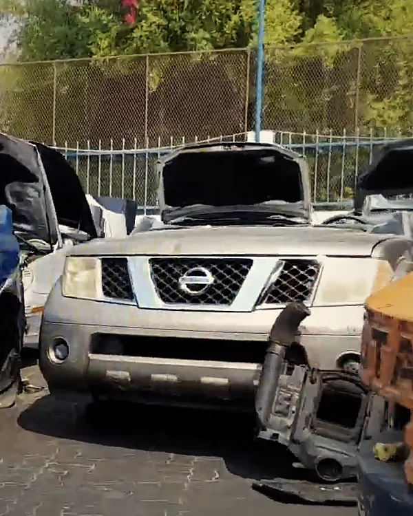 A Nissan half cut with its bonnet open in the yard